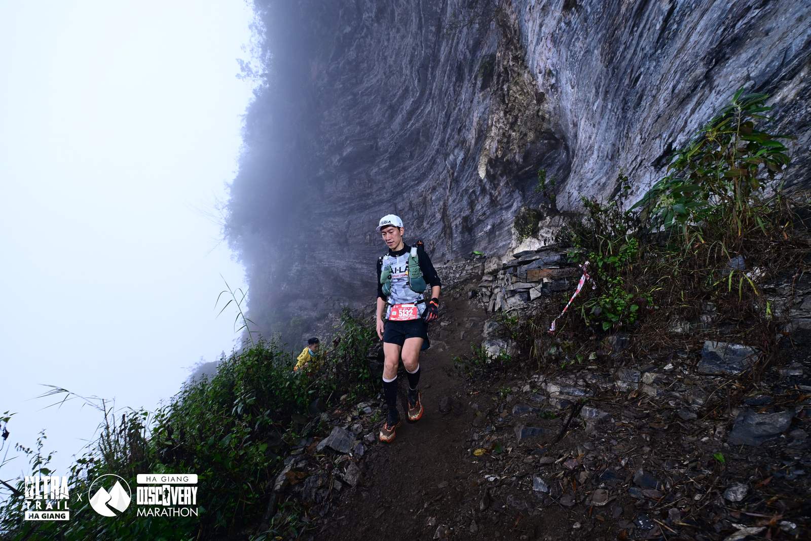 Runner đi xuống đoạn dốc đá hẹp men theo vách núi trong sương