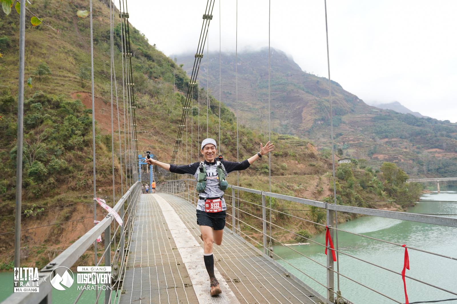 Runner giang tay ăn mừng trên cầu treo bắc qua dòng sông xanh ngọc Hà Giang